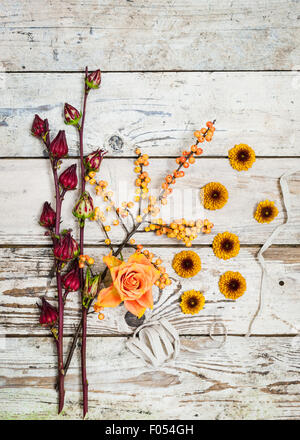 Un arrangement de fleurs et fruits d'automne aux couleurs chaudes sur un fond de bois rustique Banque D'Images