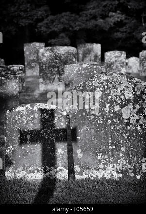 Pierre tombale croix ombre sur d'autres pierres tombales dans un cimetière. Oxfordshire, Angleterre Banque D'Images