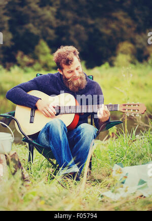 Smiling man with guitar et dixie dans camping Banque D'Images