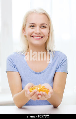 Happy woman holding des capsules d'huile de poisson à la maison Banque D'Images