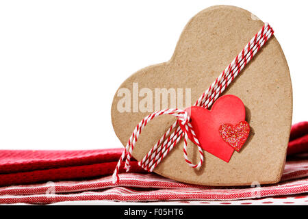 Boîte cadeau en forme de coeur avec coeur rouge tissu tag sur table Banque D'Images