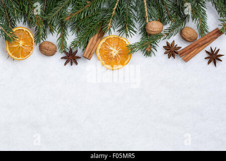 Décoration fond de Noël avec des branches de sapin, de la neige et des fruits orange Banque D'Images
