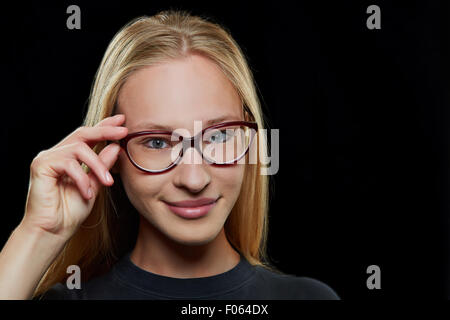 Young attractive blonde woman smiling with hand on ses lunettes Banque D'Images