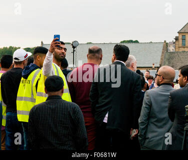 Bradford, Yorkshire, UK. 7e août, 2015. Un garde de sécurité prend une tout en selfies Jeremy Corbyn prend la parole à l'Karmand Centre Communautaire cricket ground le vendredi 7 août 2015, Bradford, West Yorkshire, UK Crédit : Graham Hardy/Alamy Live News Banque D'Images