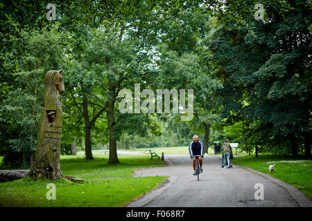 Un cycliste passant le grand arbre sculpture en mémoire des animaux morts, Woodbank Memorial Park à Offerton, Stockport, Royaume-Uni. Banque D'Images