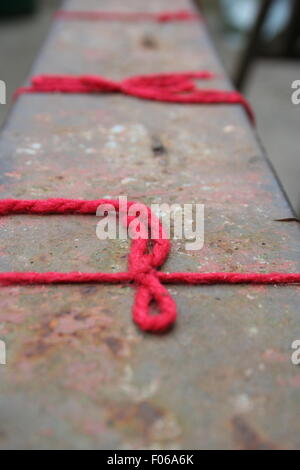 String rouge noeud sur un banc. Banque D'Images