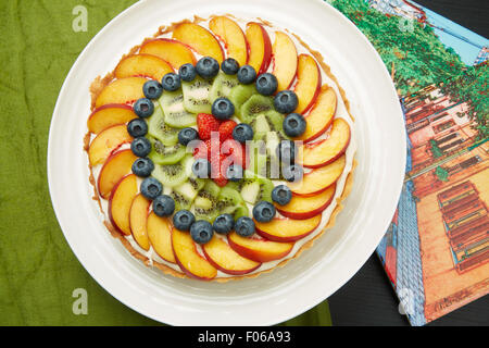 Portrait d'un délicieux gâteau avec Berry, pomme et Kiwi Fruits sur une plaque ronde blanc servi sur la table. Banque D'Images