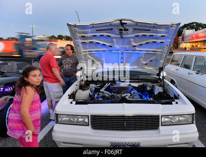 Bellmore, New York, USA. 7 août 2015. Une jeune fille et d'autres cherchent à white 1987 Chevy Monte Carlo, administré par Jean Gilson, de Islip, avec feux bleus sous capot, au vendredi soir Car Show s'est tenue à l'Bellmore Long Island Railroad Station Parking. Gilson a été l'un des nombreux membres de la South Side Boys auto club participant à la Nuit de Croisière. Des centaines de classique, antique, et les voitures personnalisées ont été à l'émission hebdomadaire libre, parrainé par la Chambre de Commerce de l'Bellmores. Banque D'Images