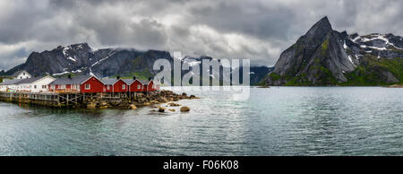 Panorama du mont Olstind au-dessus de la pêche rouge cabines appelé Rorbu dans ville de Hamnoy sur les îles Lofoten, Norvège Banque D'Images