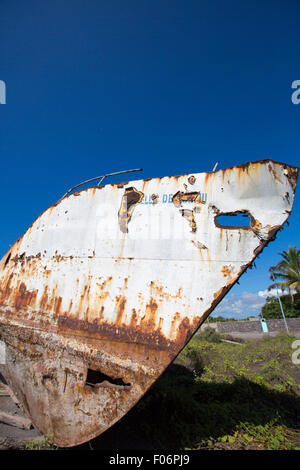 Un vieux bateau contre un ciel bleu clair, surmonté des éléments, est tiré sur la plage dans le port de Puerto Villamil. Banque D'Images