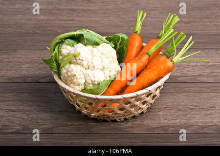 Les carottes, les choux dans une réorganisation de panier sur une table en bois Banque D'Images