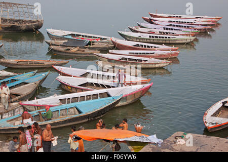 Hindu baigneurs et bateaux de plaisance amarrés sur les rives de la rivière sacrée du Gange à Varanasi en fin d'après-midi Banque D'Images