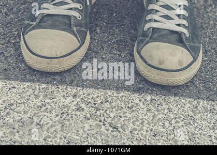 Jeune homme en attente, l'homme debout à la frontière sur la chaussée urbaine, homme pieds portant des espadrilles, selective focus, Banque D'Images