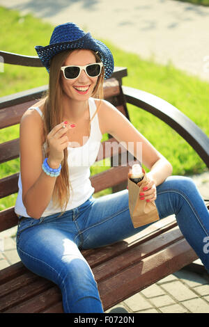 Girl drinking à partir d'un sac de papier dans la rue. fume Banque D'Images