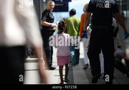 Rosenheim, Allemagne. Le 04 août, 2015. Un policier escorte un jeune fille le long d'une plate-forme à la gare de Rosenheim, Allemagne, 04 août 2015. La police allemande a ramassé autour de 150 réfugiés de différents pays dans un train entrant de Vérone. Après avoir été fouillé et enregistrés, ils ont reçu un document d'identification à un bureau de la Police Fédérale Allemande et a été envoyé à l'établissement d'accueil des réfugiés à Munich, où ils peuvent faire une demande d'asile. Photo : Andreas GEBERT/dpa/Alamy Live News Banque D'Images