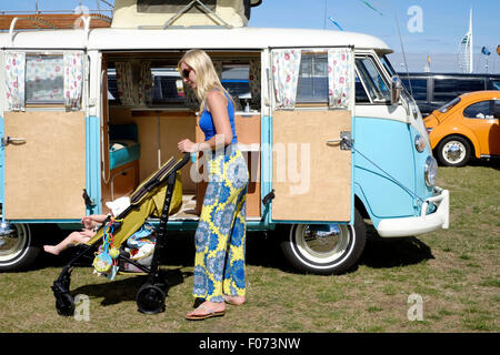 Jeune mère poussant une poussette de bébé dans un camping-car volkswagen passé à la vw car show sur southsea common england uk 2015 Banque D'Images