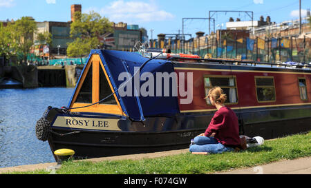 Une jeune femme est assise à côté d'un bateau étroit sur le Regent's Canal entre l'écluse et Kentish Town Hawley, Camden, London Banque D'Images