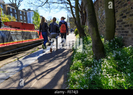 Trois filles marcher sur le chemin de halage du Regent's Canal près de Primrose Hill, Londres, avec blanc fleurs sauvages en premier plan Banque D'Images