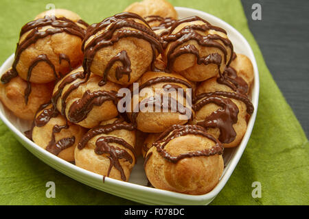 Près de délicieux pain frais avec une sauce au chocolat sur une plaque en forme de coeur servi sur la table. Banque D'Images