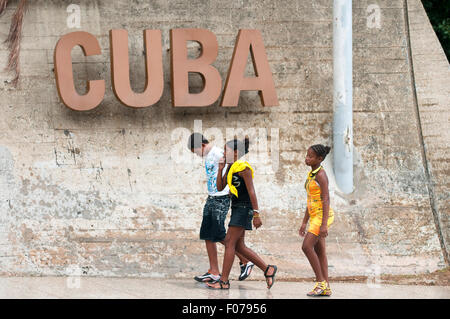 La HAVANE, CUBA - 12 juin 2011 : Groupe de jeunes cubains à pied sur le trottoir sous un grand Cuba signer le long de la Rampa street à Vedado. Banque D'Images