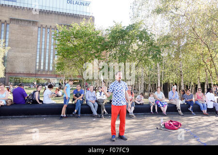 City of London, Londres, Royaume-Uni. 9 Août, 2015. Météo France : Les gens apprécient le temps chaud comme ils regardent un musicien ambulant démontrant un dangereux acte de jonglerie de poignards en dehors de la Tate Modern. La photographie d'actualité : Crédit/Alamy Live News. Banque D'Images