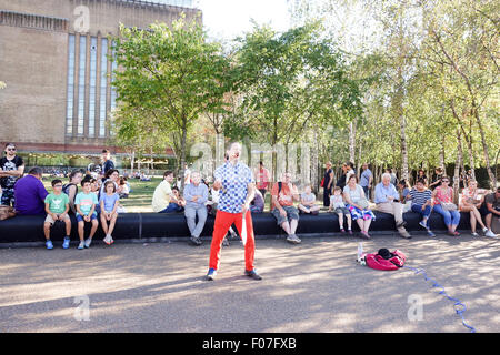 City of London, Londres, Royaume-Uni. 9 Août, 2015. Météo France : Les gens apprécient le temps chaud comme ils regardent un musicien ambulant démontrant un dangereux acte de jonglerie de poignards en dehors de la Tate Modern. La photographie d'actualité : Crédit/Alamy Live News. Banque D'Images