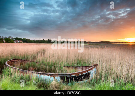 Lever de soleil sur un vieux bateau de pêche en roseaux à Hamworthy à Poole, Dorset Banque D'Images