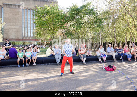 City of London, Londres, Royaume-Uni. 9 Août, 2015. Météo France : Les gens apprécient le temps chaud comme ils regardent un musicien ambulant démontrant un dangereux acte de jonglerie de poignards en dehors de la Tate Modern. La photographie d'actualité : Crédit/Alamy Live News. Banque D'Images