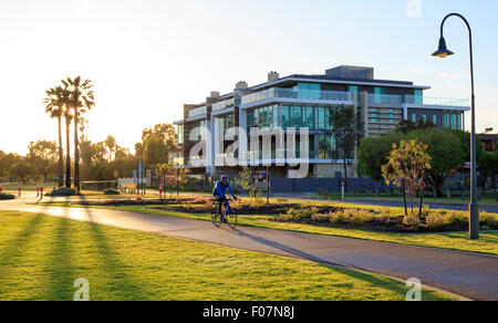 Un homme à vélo par Sir James Mitchell Park au lever du soleil. Banque D'Images