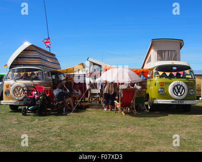 Les gens en dehors de deux camping-cars VW classique dans un champ Banque D'Images