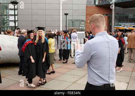 Man using tablet computer de prendre des photos de femmes diplômées de l'Université métropolitaine de Manchester après la cérémonie de remise des diplômes dans l'Homme Banque D'Images