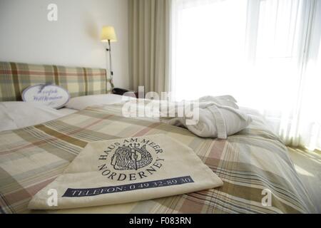 Chambre avec porte-serviettes chauffant et le couvercle sur le lit dans l'hôtel Haus am Meer, Norderney, Allemagne Banque D'Images