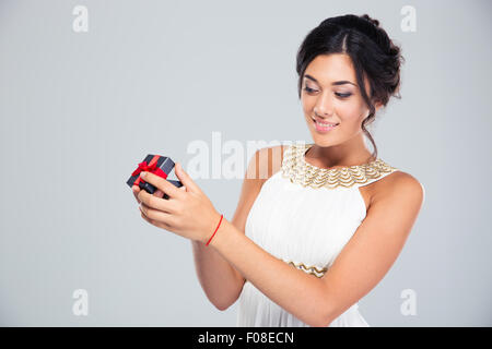 Portrait d'une jeune femme séduisante ouverture boîte cadeau bijoux sur fond gris Banque D'Images