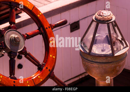 Une antique boussole et volant de dominer cette photographie nautique de l'intérieur du cockpit d'un voilier d'époque. Banque D'Images