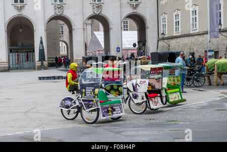 Vélo-taxi tour de ville et calèches en attente dans la Residenzplatz, Salzbourg, Autriche. Banque D'Images