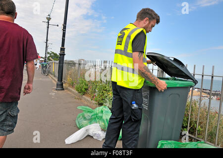 Broadstairs, Kent, Angleterre, Royaume-Uni. Homme vidange d'un bac de litière sur le front de mer Banque D'Images