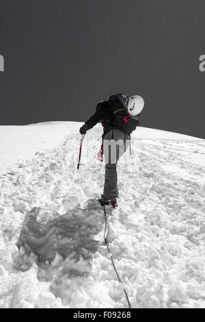 Femme climber ascending une pente enneigée. Banque D'Images