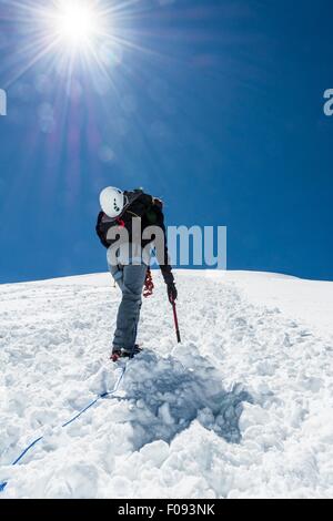 Femme climber ascending une pente enneigée. Banque D'Images