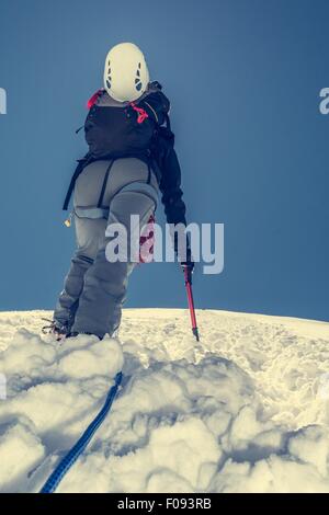 Femme climber ascending une pente enneigée. Banque D'Images