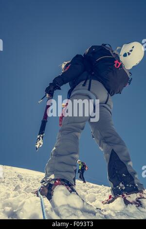 Femme climber ascending une pente enneigée. Banque D'Images