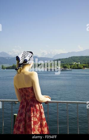 Vue arrière de la femme en rouge à la tenue en mer de Lucerne, Lucerne, Suisse resort Banque D'Images
