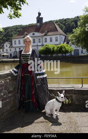 Femme vêtue traditionnellement debout à Bad Karl Harbour avec chien, Huguenot, Hesse, Allemagne Banque D'Images