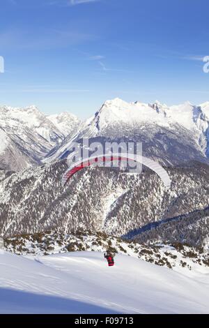 Homme parachute entre les montagnes de neige à Leutaschtal, Tyrol du Nord, Italie Banque D'Images