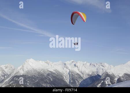 Homme parachute entre les montagnes de neige à Leutaschtal, Tyrol du Nord, Italie Banque D'Images