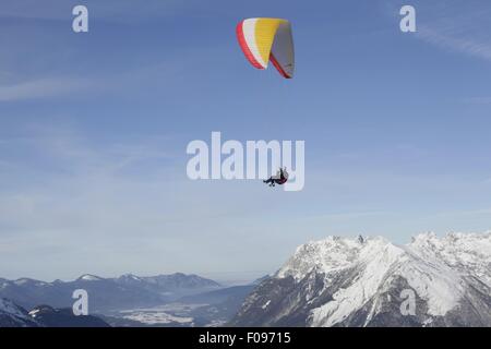 Homme parachute entre les montagnes de neige à Leutaschtal, Tyrol du Nord, Italie Banque D'Images