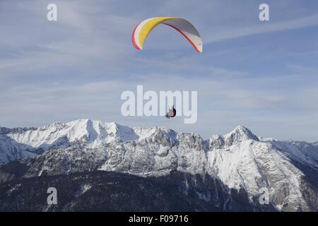 Homme parachute entre les montagnes de neige à Leutaschtal, Tyrol du Nord, Italie Banque D'Images