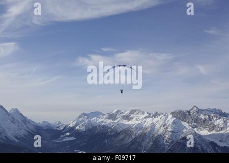 Homme parachute entre les montagnes de neige à Leutaschtal, Tyrol du Nord, Italie Banque D'Images