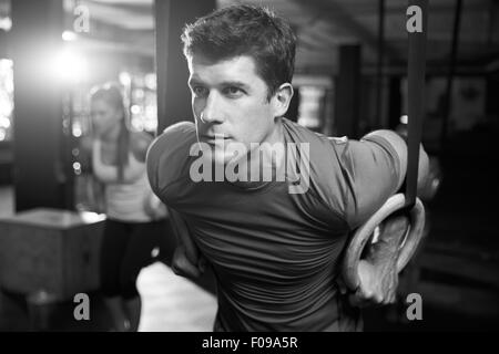 Tourné en noir et blanc de l'homme exerçant avec anneaux de gymnastique Banque D'Images