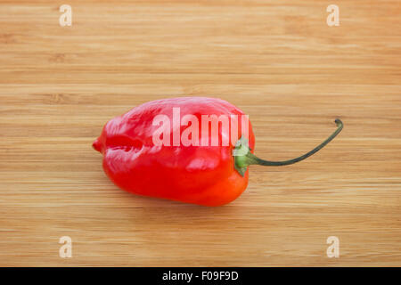 Close-up d'un ensemble de fruits rouges chili habanero sur une planche à découper en bois. Banque D'Images
