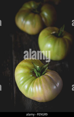 Gros fruit vert vert tomates RAF plus vieille table en bois. Style rustique foncé. La lumière naturelle du jour Banque D'Images